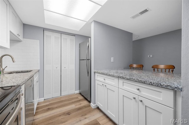 11 Fairways Cir Unit A, Saint Charles, MO 63303 - kitchen with a sink, appliances with stainless steel finishes, light wood-style flooring, white cabinets, and light stone counters