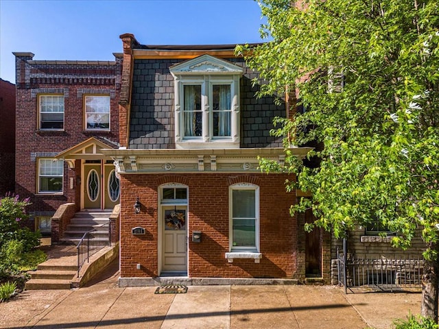 view of front of property featuring brick siding and mansard roof