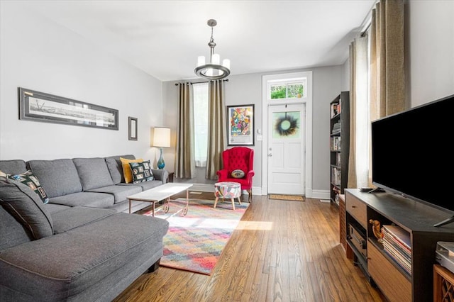 living room with wood-type flooring, baseboards, and a chandelier