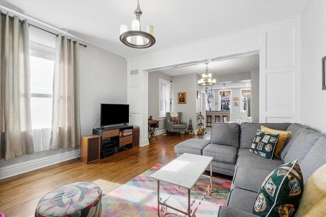 living room with a chandelier, healthy amount of natural light, wood finished floors, and baseboards