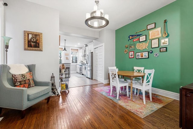 dining area featuring a chandelier, hardwood / wood-style flooring, and baseboards