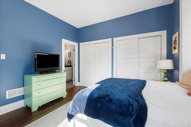 bedroom featuring multiple closets, dark wood-style floors, and baseboards