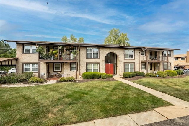view of property featuring a balcony and a front lawn