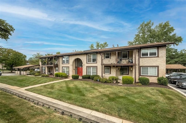multi unit property with a balcony, a front yard, and brick siding
