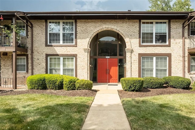 entrance to property with a yard and brick siding