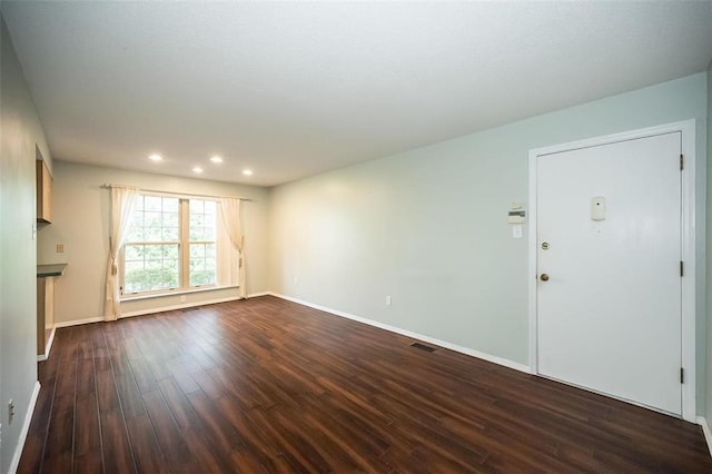 unfurnished living room with dark wood-style flooring, recessed lighting, and baseboards