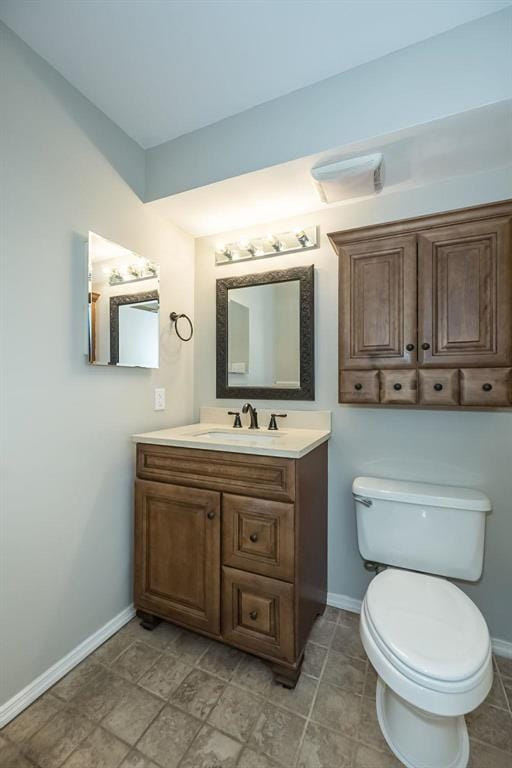 half bath with baseboards, toilet, and vanity