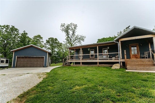 view of front of property featuring covered porch, a detached garage, a front lawn, and an outbuilding