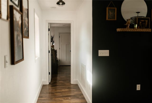 hall featuring dark wood-style flooring and baseboards
