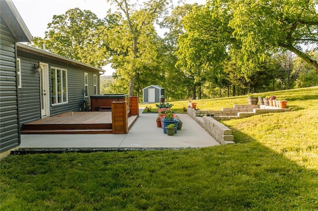 view of green lawn featuring a hot tub, a storage unit, a deck, a patio area, and an outbuilding