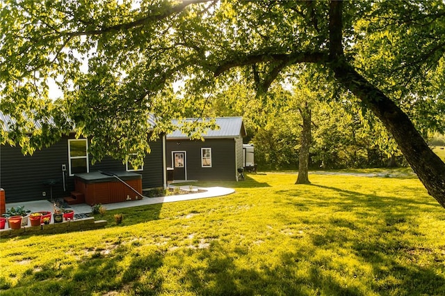 view of grassy yard featuring a hot tub and a patio