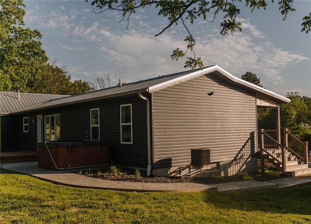 view of home's exterior featuring a hot tub, a lawn, and metal roof