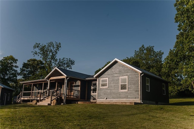 rear view of house featuring covered porch, a lawn, and metal roof