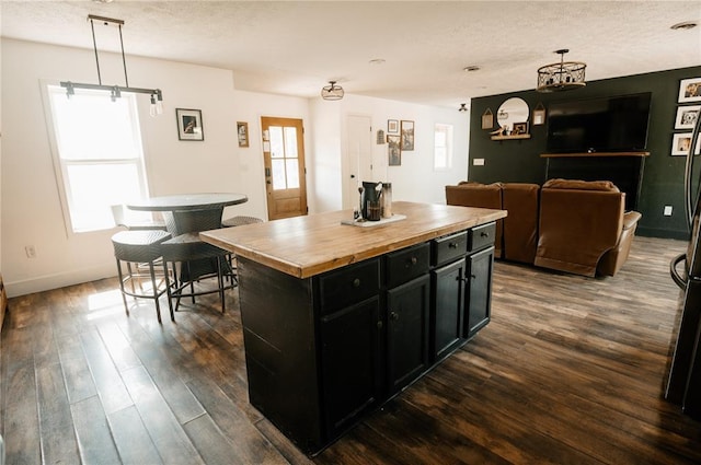 kitchen with dark cabinets, butcher block countertops, healthy amount of natural light, a textured ceiling, and dark wood-type flooring