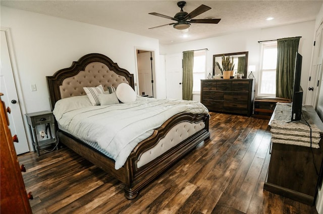 bedroom with dark wood-type flooring, a ceiling fan, and a textured ceiling