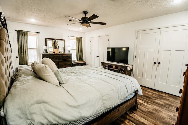 bedroom with two closets, dark wood finished floors, a textured ceiling, ceiling fan, and recessed lighting