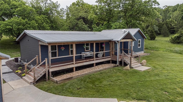 view of front facade featuring a porch, a front lawn, cooling unit, and metal roof