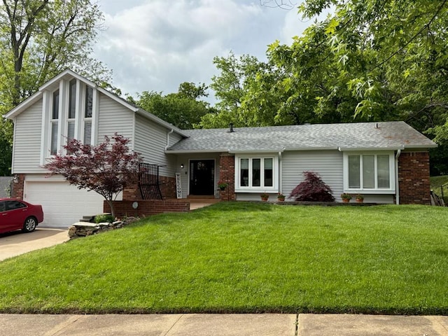 tri-level home with a front lawn, brick siding, an attached garage, and driveway
