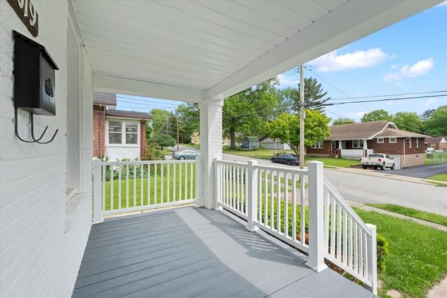 deck with a porch, a lawn, and a residential view