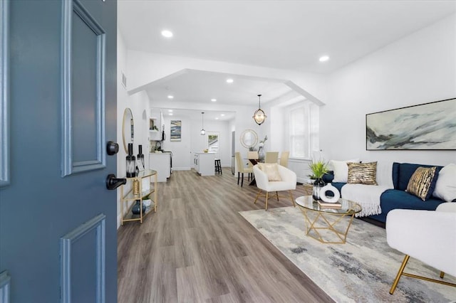 living area featuring wood finished floors, recessed lighting, and arched walkways