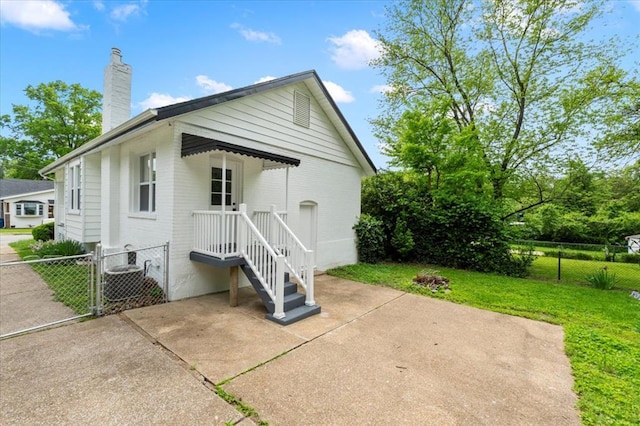 rear view of property featuring a chimney, a gate, and central AC