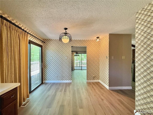 8305 Brouk Dr, Cedar Hill, MO 63016 - unfurnished dining area with baseboards, light wood-style floors, a textured ceiling, and wallpapered walls
