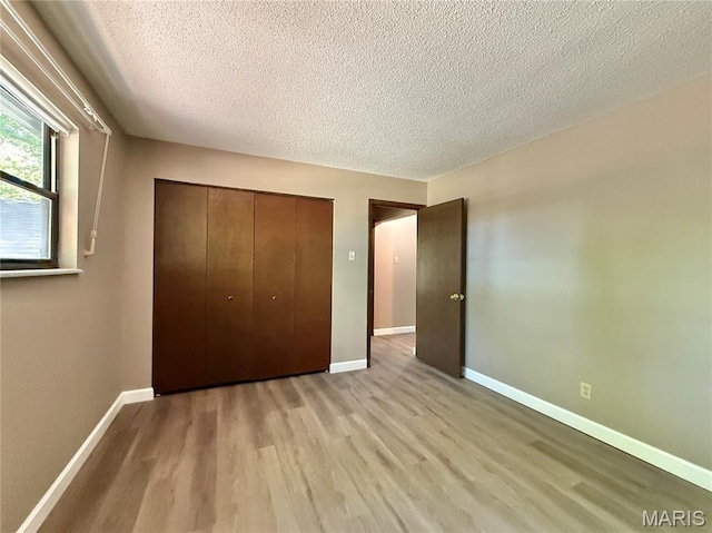 8305 Brouk Dr, Cedar Hill, MO 63016 - unfurnished bedroom with light wood finished floors, a textured ceiling, baseboards, and a closet