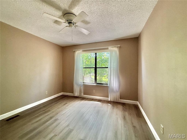 8305 Brouk Dr, Cedar Hill, MO 63016 - empty room with wood finished floors, a textured ceiling, a ceiling fan, and baseboards