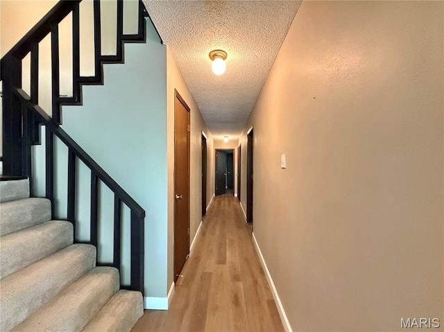 8305 Brouk Dr, Cedar Hill, MO 63016 - corridor with a textured ceiling, light wood-style floors, baseboards, and stairway