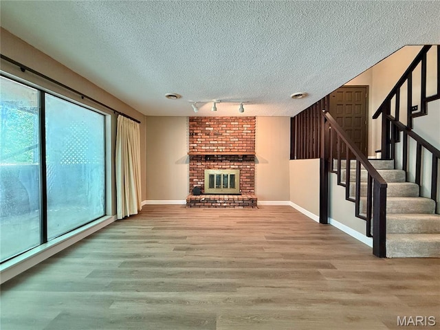 8305 Brouk Dr, Cedar Hill, MO 63016 - unfurnished living room featuring healthy amount of natural light, a textured ceiling, wood finished floors, and stairway