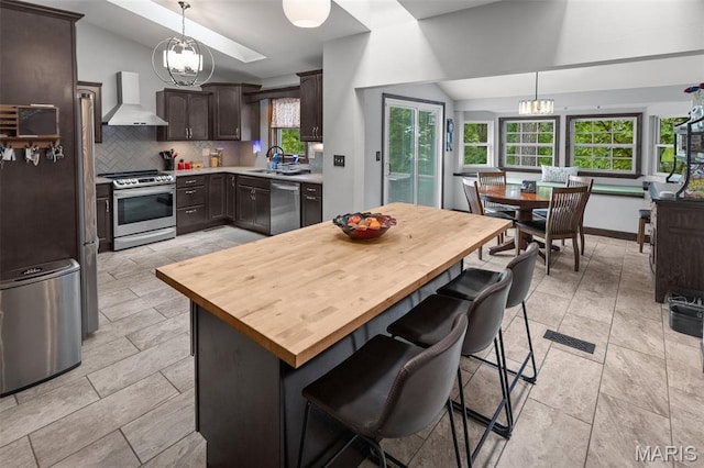 7 Tall Oaks Dr, Troy, IL 62294 - kitchen featuring stainless steel appliances, wall chimney exhaust hood, lofted ceiling, butcher block counters, and dark brown cabinetry