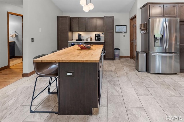 7 Tall Oaks Dr, Troy, IL 62294 - kitchen featuring stainless steel refrigerator with ice dispenser, butcher block counters, dark brown cabinets, a breakfast bar, and a kitchen island