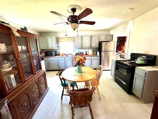 201 E 2nd N St, Mount Olive, IL 62069 - kitchen with black range with electric cooktop, a ceiling fan, gray cabinets, freestanding refrigerator, and a sink
