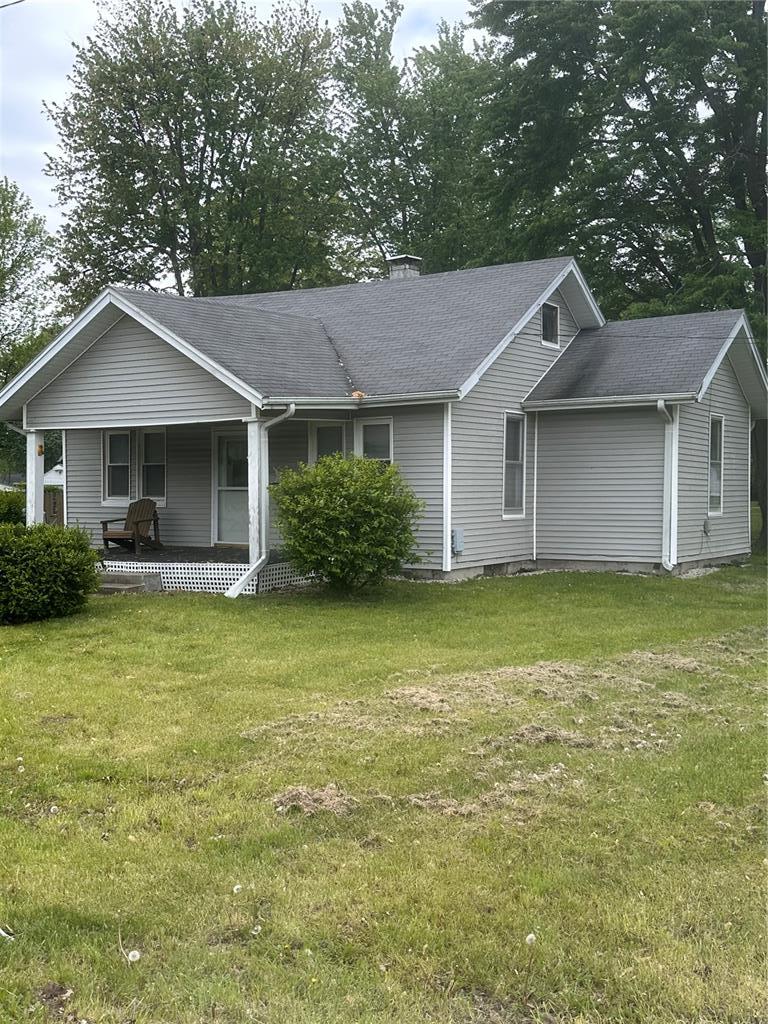 605 N Locust St, Monroe City, MO 63456 - view of front facade featuring covered porch, a front yard, a chimney, and roof with shingles