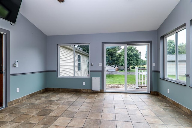 spare room with lofted ceiling, healthy amount of natural light, and baseboards