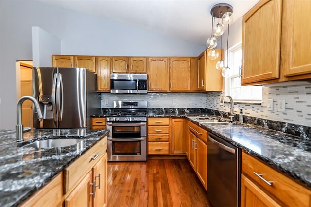 kitchen with stainless steel appliances, a sink, lofted ceiling, dark wood-style flooring, and hanging light fixtures