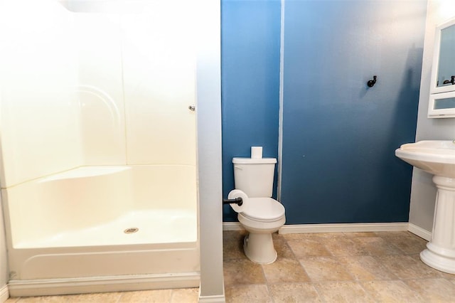 full bathroom with baseboards, toilet, a shower, stone finish floors, and a sink