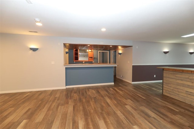 unfurnished living room featuring dark wood-style floors, baseboards, and bar