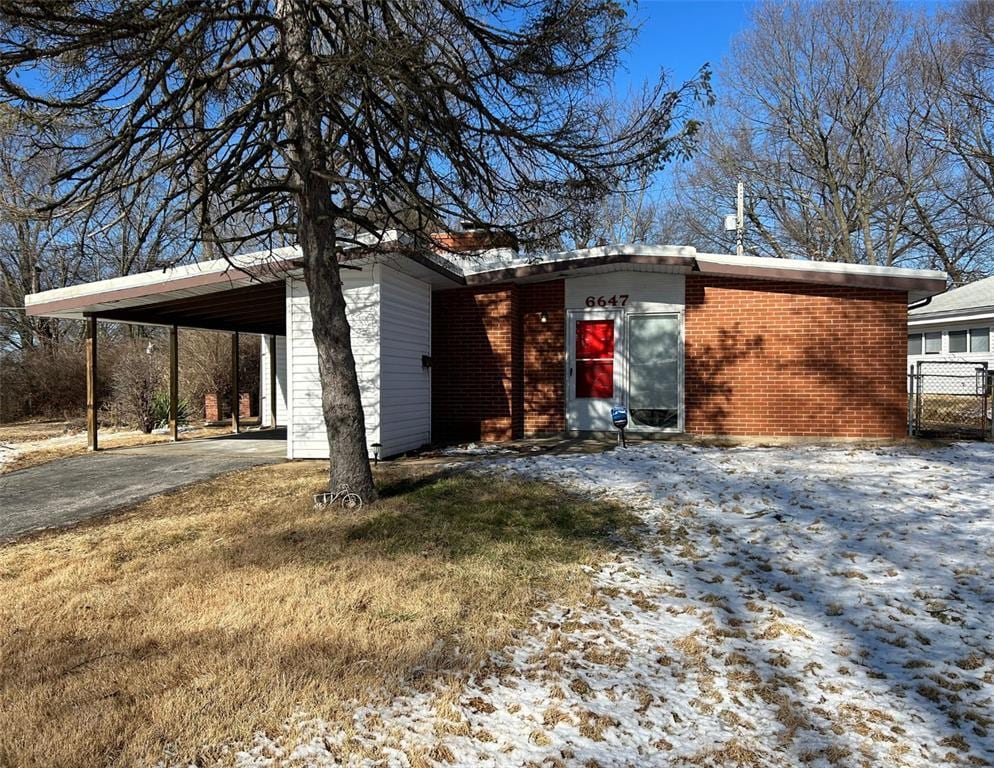 view of front facade featuring driveway, brick siding, and a carport