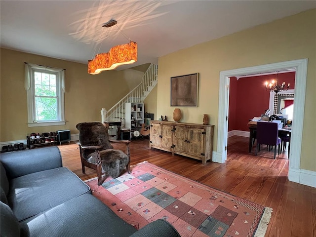 living room featuring dark wood finished floors, a chandelier, stairs, and baseboards