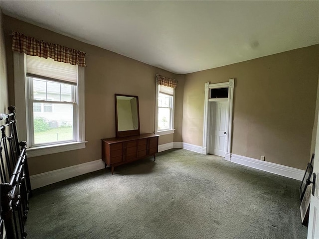 unfurnished bedroom with carpet flooring, multiple windows, and baseboards