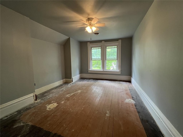 empty room with hardwood / wood-style floors, a ceiling fan, and baseboards