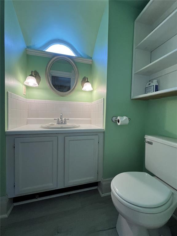 half bath featuring toilet, tasteful backsplash, and vanity