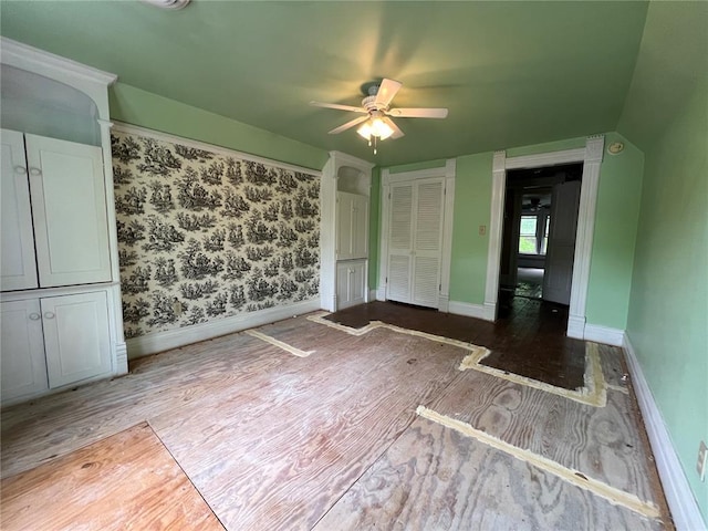 unfurnished bedroom featuring wood finished floors, baseboards, and a ceiling fan