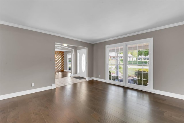 empty room with healthy amount of natural light, baseboards, hardwood / wood-style flooring, and crown molding