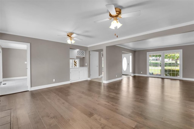 unfurnished living room featuring a ceiling fan, wood finished floors, ornamental molding, and baseboards