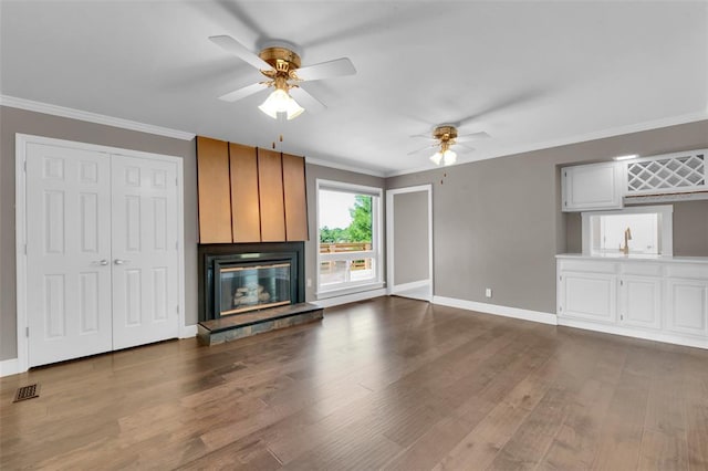 unfurnished living room with ceiling fan, baseboards, dark wood-style floors, and ornamental molding
