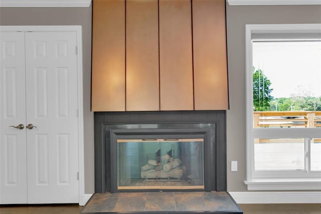 detailed view of baseboards, a tile fireplace, and ornamental molding