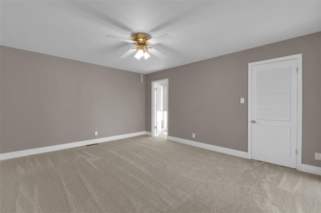 empty room featuring ceiling fan, light colored carpet, and baseboards