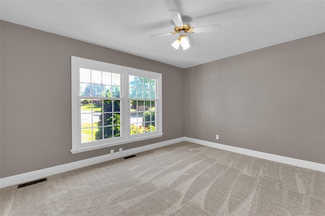 unfurnished room featuring plenty of natural light, baseboards, light colored carpet, and ceiling fan